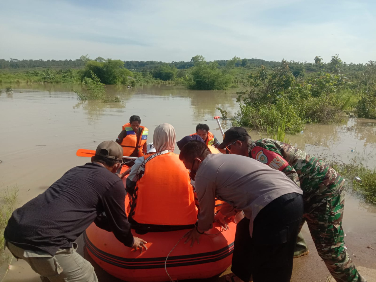 Dalam Motto “Satu Hari Satu Kebaikan” anggota TNI membantu warga menyebarangi jalan dari luapan air bendungan Sadawarna