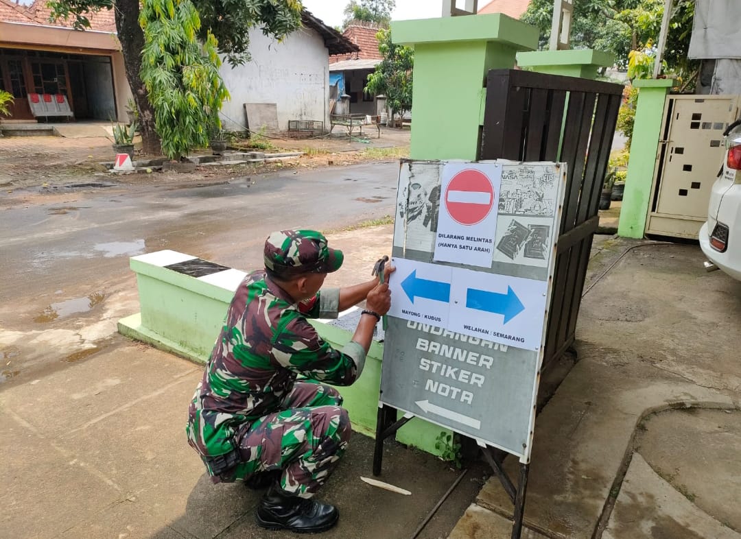Babinsa Tigajuru Monitoring Pemasangan Papan Penunjuk Arah di Lokasi Perbaikan Jembatan